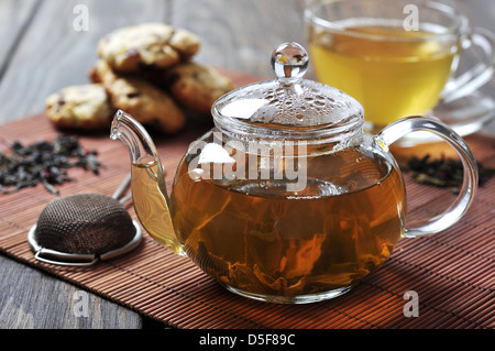 Il tè verde nella tazza e teiera con i cookie su sfondo di legno Foto Stock