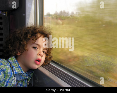 Little Boy annoiato sul viaggio In treno Foto Stock