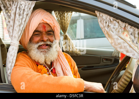 Sadhu seduto in macchina e sorridente durante il primo royal bath processione in Kumbh Mela festival di Allahabad Uttar Pradesh, India Foto Stock