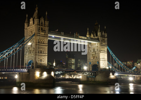 Il Tower Bridge illuminato di notte, con il fiume Tamigi in primo piano, East London, England, Regno Unito Foto Stock