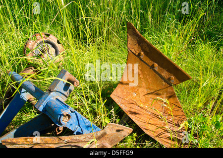 Il vecchio trattore arrugginito aratro su erba estate in fattoria Foto Stock