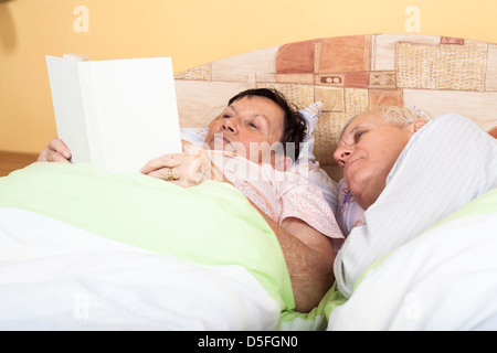 In prossimità di due anziani libro di lettura a letto. Foto Stock