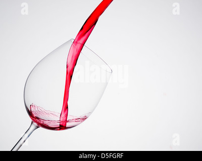 Versando il vino in un vetro di composizione diagonale e sfondo bianco Foto Stock