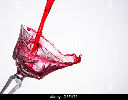 Versando il vino in un vetro di composizione diagonale e sfondo bianco Foto Stock