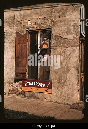 Un'immagine degli anni '1940 di Natchez, Mississippi, che mostra edifici in decadenza con pubblicità vintage per Orange Crush e Royal Crown Cola, insieme a cartelli da negozio di peeling. Foto Stock