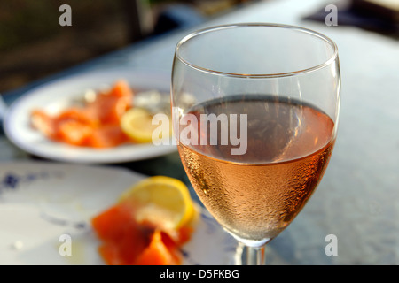 Bicchiere di fresco vino rosato, salmone affumicato in background Foto Stock