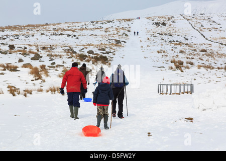 La gente camminare e slittino in montagne di Snowdonia durante unseasonably freddo e nevicate. Conwy North Wales UK Foto Stock