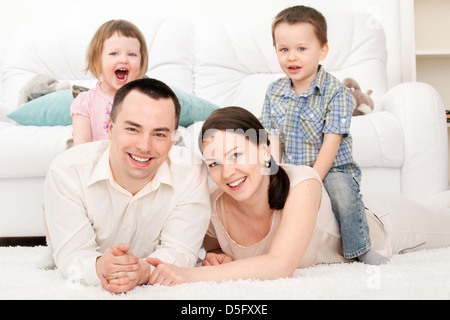 Famiglia giacente su un tappeto nel loro salotto Foto Stock