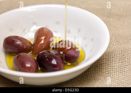 Le olive in olio di oliva in bianco vaso in ceramica Foto Stock