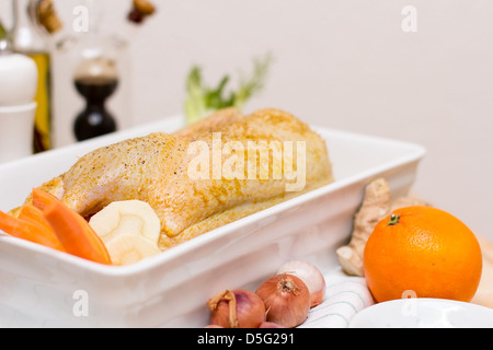 Il pollo crudo di carne con cipolle, carote e arancio in bianco piatto di supporto Foto Stock