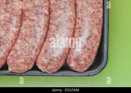 Carne cruda salsiccia, brat,in plastica nera su sfondo verde, Foto Stock