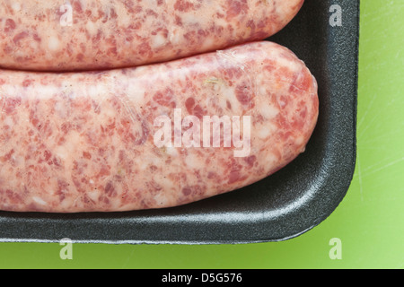 Carne cruda salsiccia, brat,in plastica nera su sfondo verde, Foto Stock