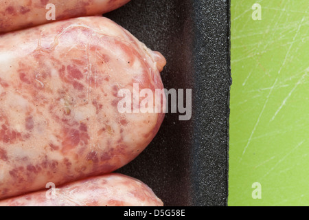 Carne cruda salsiccia, brat,in plastica nera su sfondo verde, Foto Stock