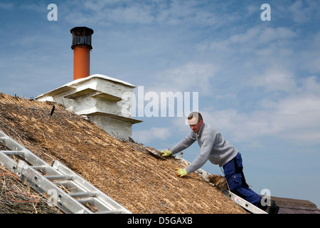 Isola di Man, Cregneash, la Thatcher ri-ricoprendo di paglia tetto cottage Foto Stock