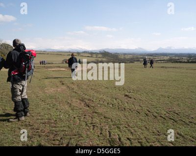 Llangaffo Anglesey North Wales Walkers su un led di escursionisti a piedi con vedute al coperto di neve montagne di Snowdonia Foto Stock