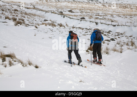 Conwy Galles del Nord marzo due montare uomini sani lo sci di fondo lungo una coperta di neve via esercitare il Parco Nazionale di Snowdonia Foto Stock