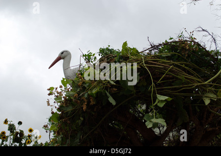 Plastica decorativa stork sedersi nel nido fatti a mano dalle piante del superriduttore sul sullo sfondo di un cielo nuvoloso. Foto Stock