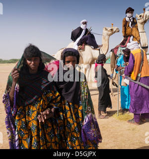Wodaabe donne nomadi sostare davanti a un gruppo di uomini Wodaabe sui cammelli nel nord del Niger Foto Stock