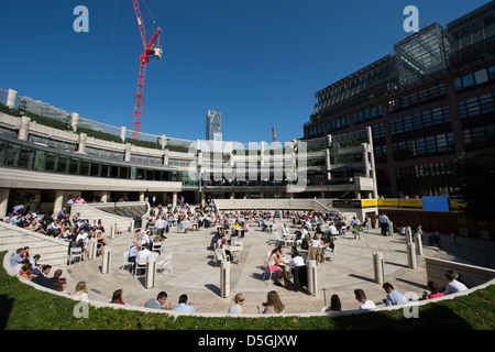 I lavoratori della città gustando un pranzo all'aperto a Broadgate e Exchange Square zona vicino alla stazione di Liverpool Street, Londra, Inghilterra. Foto Stock
