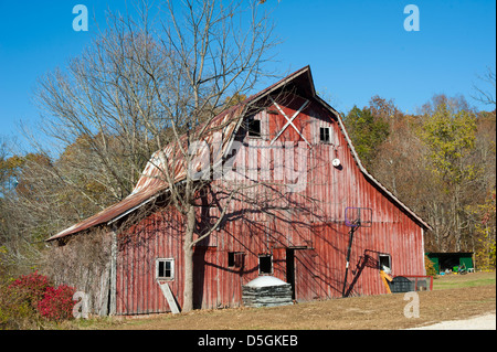 Un vecchio rosso weathered fienile stoicly sorge su un nitido mattina autunnale. Foto Stock