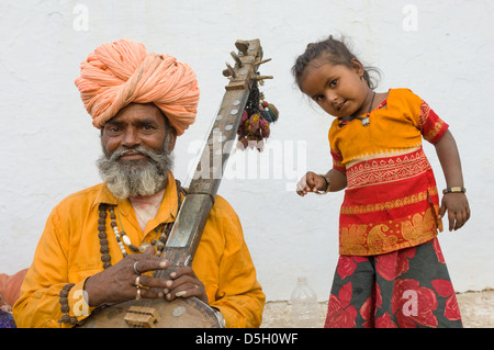 Musicista tenendo un sitar con la sua giovane figlia balli presso il Pushkar Mela, Pushkar, Rajasthan, India Foto Stock