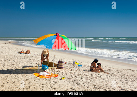 Madagascar, Morondava, spiaggia, turisti francesi a prendere il sole sotto ombrellone colorato Foto Stock