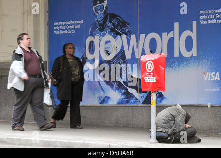 Un senzatetto si siede di fronte a un poster pubblicitari le Olimpiadi Invernali 2010 a Vancouver, Canada, 03 febbraio 2010. La '2010 povertà Olypmics" si svolgerà il 07 febbraio 2010 come una manifestazione di protesta per i Giochi Olimpici Invernali. Il numero di senzatetto in Vancouver è superiore alla media; secondo gli organizzatori, il bambino il tasso di povertà nella provincia canadese British C Foto Stock