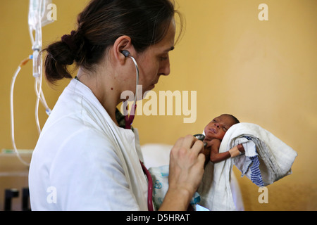 Femmina medico tedesco esaminando neonato bambino africano. Ospedale di Techiman il, Ghana Foto Stock