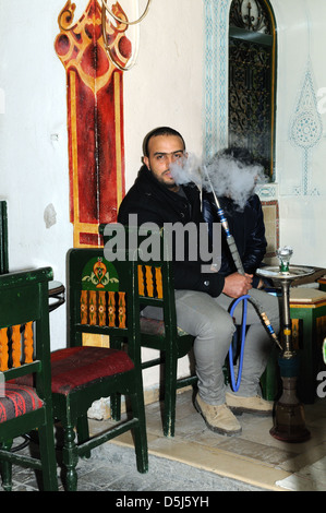 Uomo tunisino fumare una shisha in un cafe nella vecchia Medina Tunisi Tunisia Foto Stock