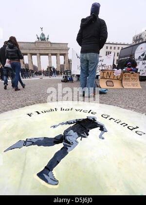 Un banner sdraiato sul pavimento si legge: "Ci sono molte ragioni per il volo!' nella parte anteriore della porta di Brandeburgo a Berlino, Germania, 16 novembre 2012. I rifugiati che sono state protestando per Pariser Platz per le ultime tre settimane intende rafforzare le loro richieste per un miglioramento della loro situazione giuridica con un nuovo sciopero della fame. Foto: STEPHANIE PILICK Foto Stock