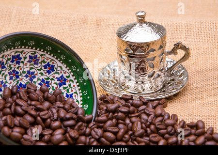 Un autentico caffè turco cup con i chicchi di caffè. I chicchi di caffè versato su tela da dipinto a mano in ceramica. Foto Stock