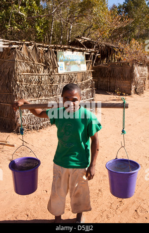 Madagascar, Funzionamento Wallacea, Matsedroy forest camp, locale uomo che lavora come vettore acqua con secchi di acqua sul giogo di spallamento Foto Stock