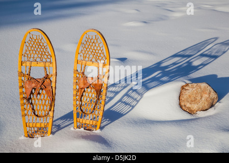 Una coppia di classico Bear Paw di racchette da neve in legno gettato ombra nella neve Foto Stock