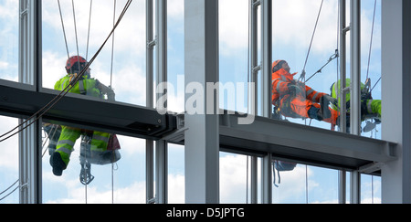 Appesi a corde sulla faccia esterna di una torre di Londra edificio a blocco di eseguire lavori di manutenzione Foto Stock