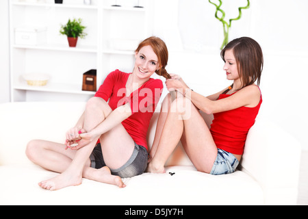 Giovane donna calza il suo amico i capelli seduto sul divano di casa. Foto Stock