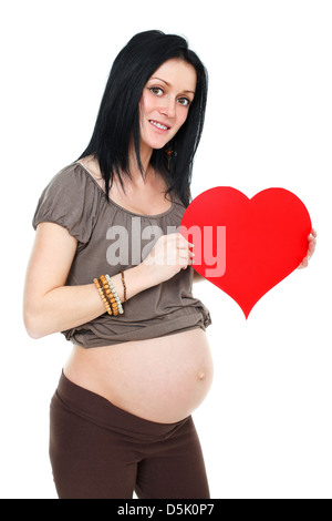 Sorridente bella donna incinta tenendo un cuore rosso su sfondo bianco Foto Stock