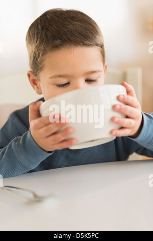 Ragazzo (4-5) di bere dalla ciotola Foto Stock