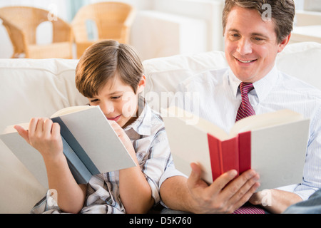 Father and son (8-9) reading books Foto Stock