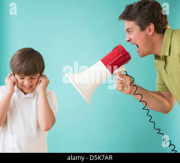 Padre con megafono urla al figlio (8-9) Foto Stock