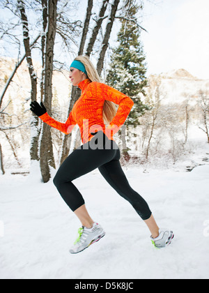 Stati Uniti d'America, Utah, Salt Lake City, Donna jogging nel bosco invernale Foto Stock