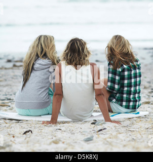 Vista posteriore della gente seduta sulla spiaggia Foto Stock