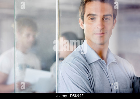 Ritratto di uomo con i colleghi di lavoro in background Foto Stock