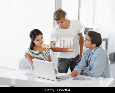 I colleghi parlando a tavola, utilizzando laptop Foto Stock