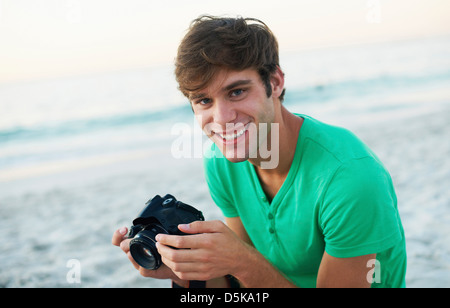 Ritratto di giovane uomo di scattare foto in spiaggia Foto Stock