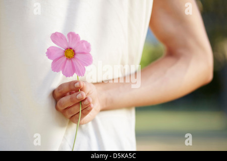 Uomo con fiore dietro indietro Foto Stock