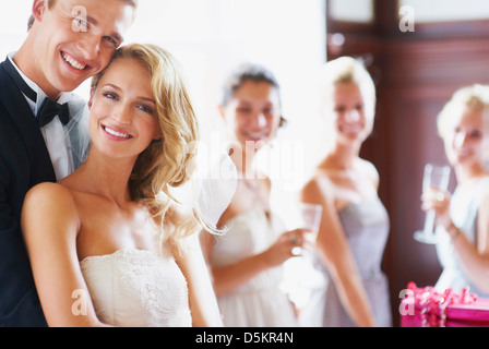 Ritratto di coppia di novelli sposi, bridesmaids in background Foto Stock