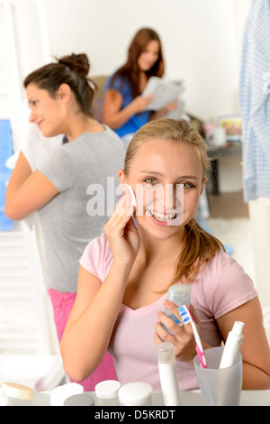 Ragazza adolescente pulizia viso con tampone di cotone con i suoi amici Foto Stock