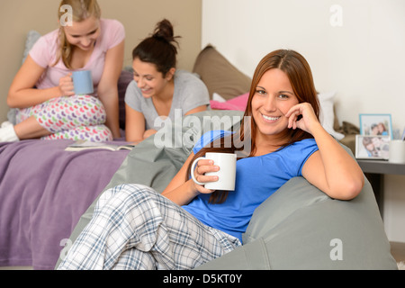 Adolescente ragazze lettura e bere a slumber party Foto Stock