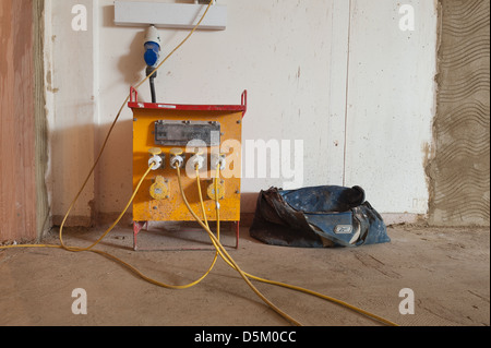 Costruttori borsa da lavoro accanto a un heavy duty giallo 110 volt edificio alimentazione trasformatore di isolamento andato per il tè in pausa pranzo Foto Stock