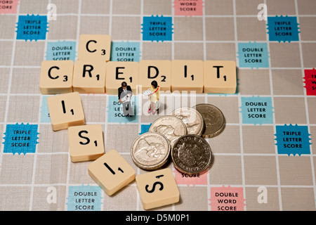 Piastrelle sulla lavagna di Scrabble che scrivono crisi creditizia, con uomo e donna giocattolo e concetto di finanza aziendale di recessione in contanti delle monete inglesi Foto Stock